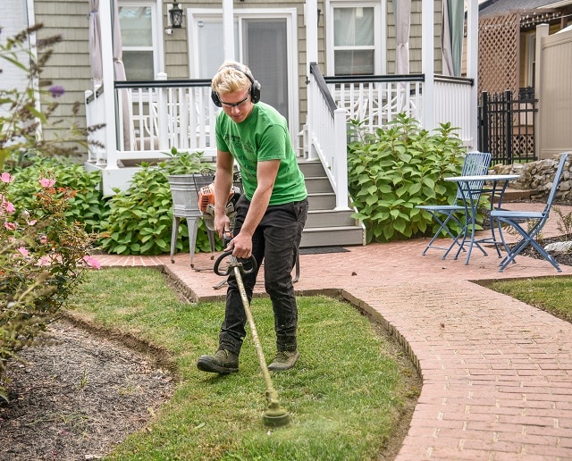 a man is tacking care of his yard with a string trimmer